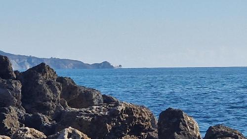 a large body of water with rocks in the foreground at Namastè Apartments Agrigento in Agrigento