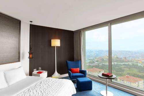 a bedroom with a bed and a blue chair and a window at Le Meridien Istanbul Etiler in Istanbul