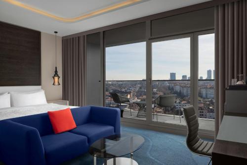 a hotel room with a blue couch and a large window at Le Meridien Istanbul Etiler in Istanbul