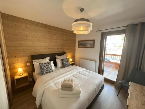 - une chambre avec un lit blanc et un mur en bois dans l'établissement Apprt moderne 70m2, 3 chbr, 6 pers, sur les pistes, tout équipé, garage intérieur, au Grand-Bornand