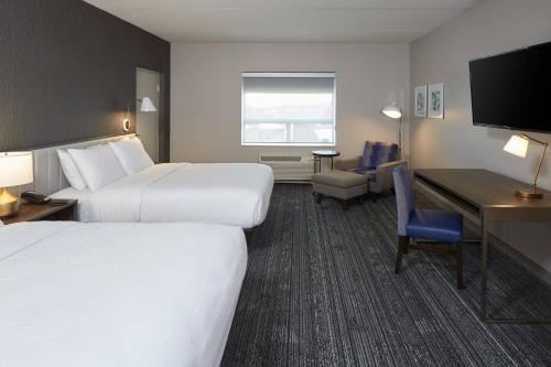 a hotel room with two beds and a desk at TownePlace Suites by Marriott Hamilton in Hamilton