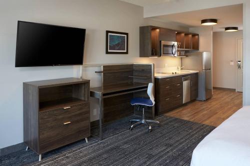 a hotel room with a bed and a desk with a television at TownePlace Suites by Marriott Hamilton in Hamilton
