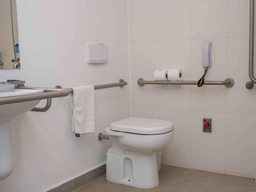 a white bathroom with a toilet and a phone at ibis budget Campinas Aquidaban in Campinas