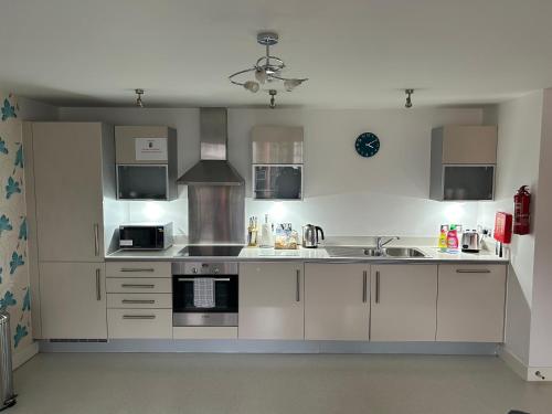 a kitchen with white cabinets and a stove top oven at Vizion Suites Milton Keynes - Free WiFi, Netflix Secure, Parking, Fully Furnished & Equipped Apartments in Milton Keynes