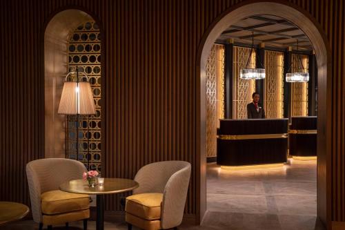 a man standing in a lobby with a table and chairs at Maison Rouge Strasbourg Hotel & Spa, Autograph Collection in Strasbourg