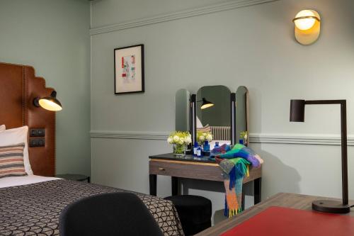 a bedroom with a desk with a bed and a mirror at Maison Rouge Strasbourg Hotel & Spa, Autograph Collection in Strasbourg