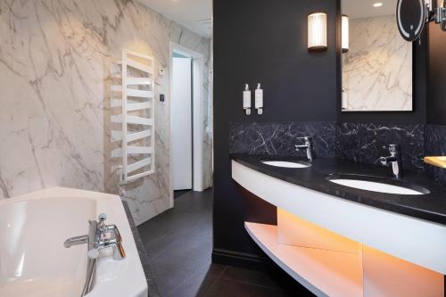 a bathroom with two sinks and a tub at Maison Rouge Strasbourg Hotel & Spa, Autograph Collection in Strasbourg