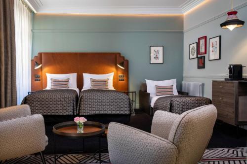 a hotel room with two beds and two chairs at Maison Rouge Strasbourg Hotel & Spa, Autograph Collection in Strasbourg