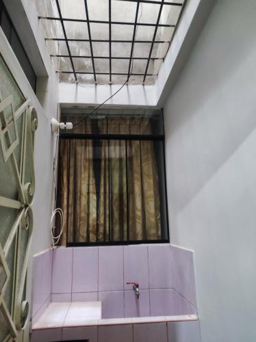 a bathroom with a window and a pink tile wall at no disponibl in Trujillo