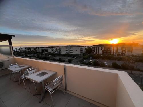 d'un balcon avec des tables et des chaises et un coucher de soleil. dans l'établissement La Goelette T3 rayonnant parking 6 pers max, à Sète