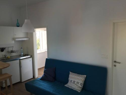 a blue couch in a living room with a kitchen at Perfect apartment in nature park in Lukovo Šugarje