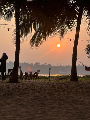 a person walking on the beach at sunset at Zone 51 Malpe - Beach Camping Experience in Malpe