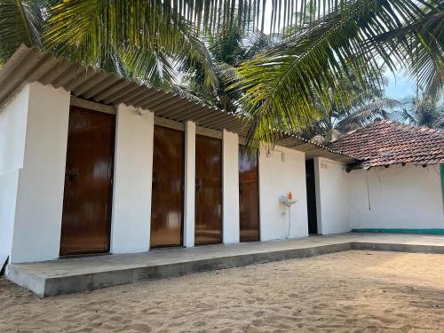 a building with wooden doors and a palm tree at Zone 51 Malpe - Beach Camping Experience in Malpe