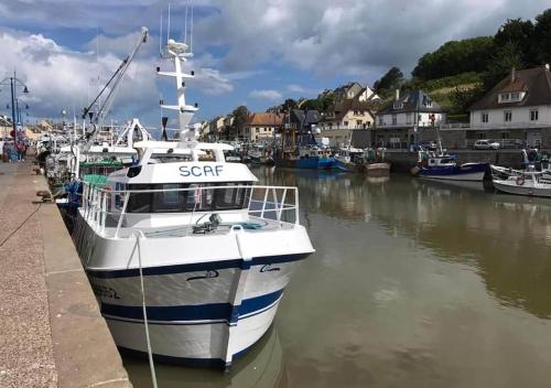a boat is docked at a dock in the water at Appartement lumineux et cosy avec jardin vue sur chateau près Port en Bessin, Bayeux et Omaha Beach in Commes