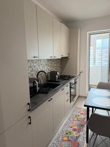 a kitchen with white cabinets and a table and a window at RULU Studio Militari Residence Ballroom in Roşu