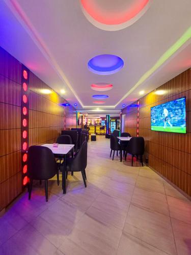 a dining room with tables and chairs and a tv at Presken Hotels Alade Avenue in Ikeja