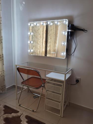a glass desk with a chair in front of a mirror at Homestay Medina Sendayan in Kampong Baharu Jimah