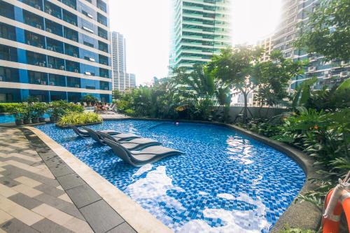 马尼拉Cozy Peacock hideaway Stylish Makati Condo 300 Mbps Gym Swim Park的一座位于城市中心,拥有高楼建筑的游泳池