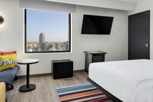 a bedroom with a bed and a large window at Aloft Santo Domingo Piantini in Santo Domingo