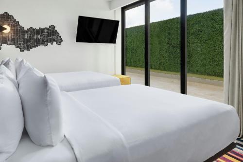 a white bedroom with a couch and a tv at Aloft Santo Domingo Piantini in Santo Domingo