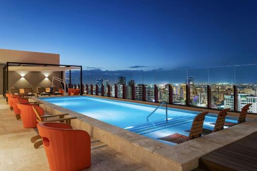 a swimming pool on top of a building with a city skyline at Aloft Santo Domingo Piantini in Santo Domingo
