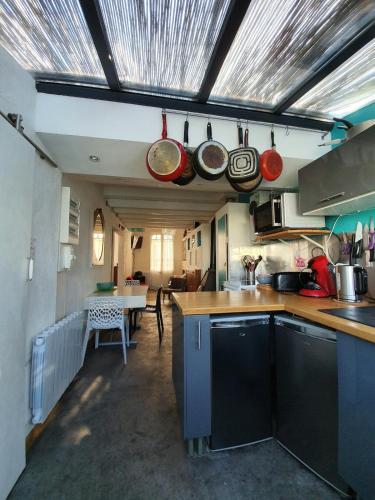 une cuisine avec des casseroles suspendues au plafond dans l'établissement charmante maisonnette a 400m de la plage, à Noirmoutier-en-l'lle