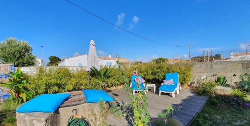 une terrasse avec 2 chaises bleues, une table et une clôture dans l'établissement charmante maisonnette a 400m de la plage, à Noirmoutier-en-l'lle