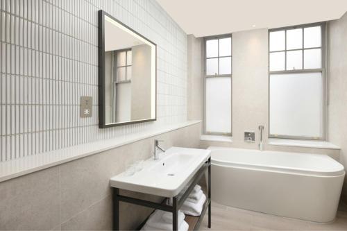 a bathroom with a sink and a tub and a mirror at AC Hotel by Marriott Glasgow in Glasgow