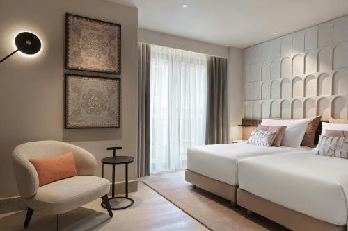 a bedroom with a white bed and a chair at MonAsty, Thessaloniki, Autograph Collection in Thessaloniki