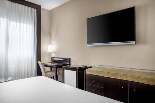 a hotel room with a bed and a flat screen tv at AC Hotel Oviedo Fórum by Marriott in Oviedo