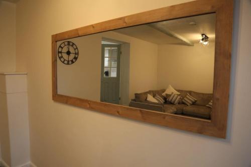 a mirror on a wall with a couch in a room at White Swan Cottage 2 in Hunmanby