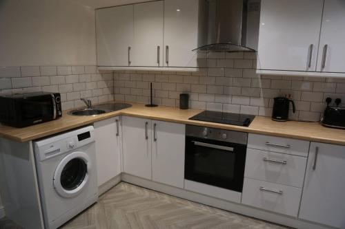 a kitchen with white cabinets and a washer at White Swan Cottage 2 in Hunmanby