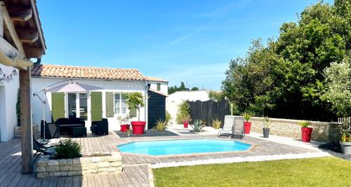 une cour arrière avec une piscine et une maison dans l'établissement Charmante maison familiale, à Sainte-Marie de Ré