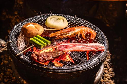 a grill with meat and vegetables on it at ログコテージ茶臼の森 in Nasu