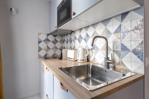 un comptoir de cuisine avec un évier en acier inoxydable dans l'établissement Relax in a Contemporary Designer Apartment, à Paris