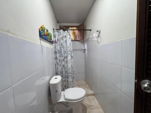 a small bathroom with a toilet and a shower at Casa Aventureros Isla Grande Colombia in Cartagena de Indias
