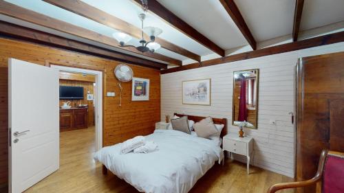 a bedroom with a white bed and a wooden wall at בית הזורע של רשת לב הגולן - 4 צימרים מדהימים עם בריכה משותפת ליד הכנרת in Menaẖemya