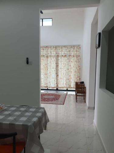 a living room with a table and a television and a window at Nur Maju Homestay in Kota Bharu