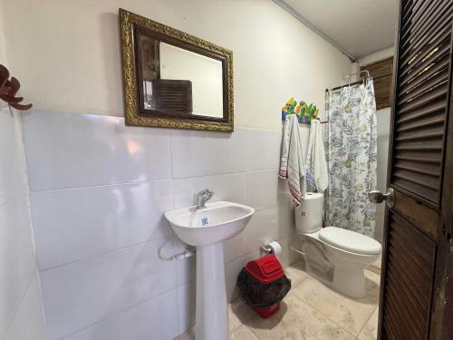 a bathroom with a sink and a toilet and a mirror at Casa Aventureros Isla Grande Colombia in Cartagena de Indias