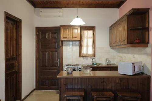 a kitchen with wooden cabinets and a white microwave at Nikos Pool Apartments - Upper Floor in Sidari