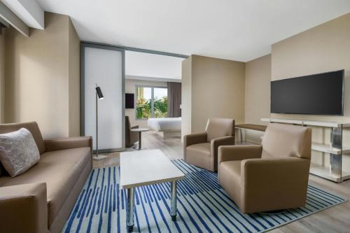 a living room with a couch and chairs and a flat screen tv at AC Hotel St Petersburg Downtown in St Petersburg