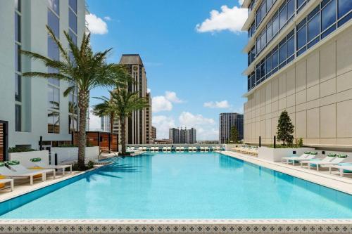 a large swimming pool with palm trees and buildings at AC Hotel St Petersburg Downtown in St Petersburg