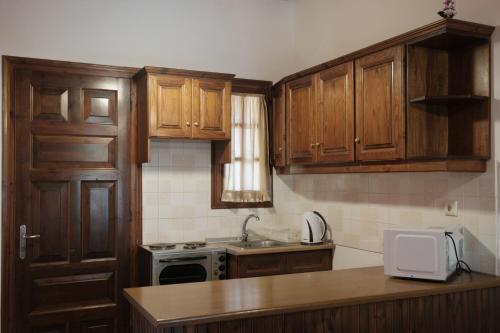 a kitchen with wooden cabinets and a sink and a microwave at Nikos Pool Apartments - Upper Floor in Sidari