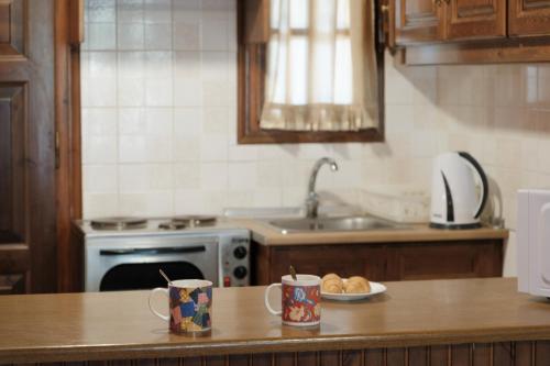 a kitchen with a counter with two mugs and a plate of bread at Nikos Pool Apartments - Upper Floor in Sidari