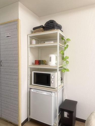 a white shelf with a microwave in a room at Shinjuku Kabukicho 新宿最中心 東新宿5分 新宿9分 MAX4人 直達 渋谷原宿上野秋葉原 in Tokyo