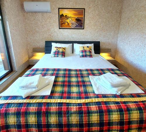 a bedroom with a bed with a plaid blanket at Forest View Apartment in Shkorpilovtsi