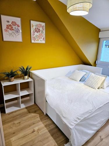 une chambre avec un lit blanc et un mur jaune dans l'établissement Maison - Cosy - Baie d'Authie, à Berck-sur-Mer