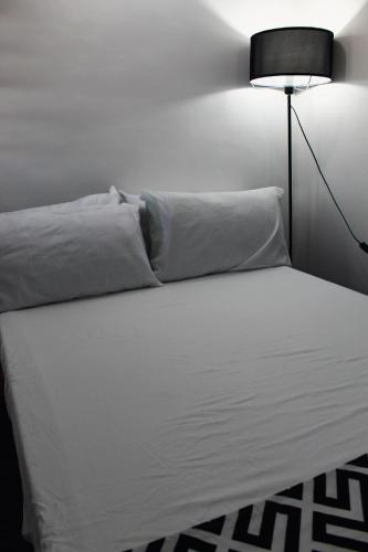 a bed with white sheets and a black lamp at Caryolba hometel - Calapan in Calapan