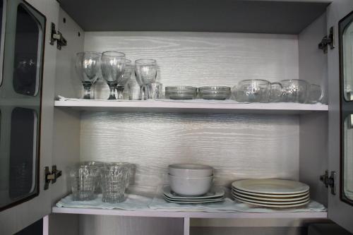 a cupboard filled with glasses and plates and bowls at Caryolba hometel - Calapan in Calapan