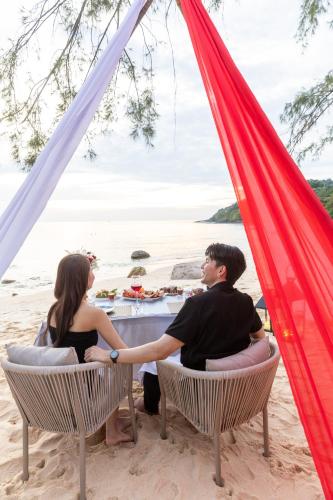 a couple sitting at a table in a tent on the beach at Ajinta Resort in Ko Kood